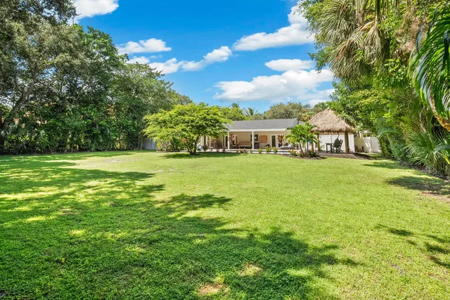 a view of a patio with table and chairs under an umbrella with a small yard