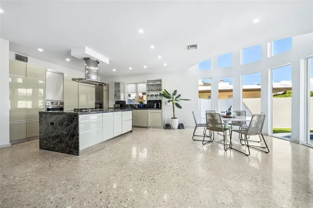 a large living room with stainless steel appliances kitchen island granite countertop a table and chairs in it