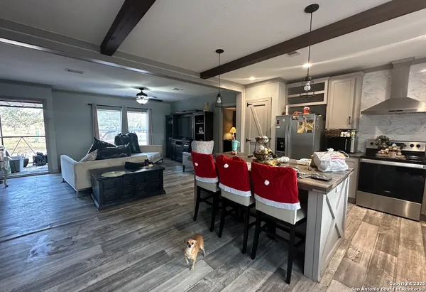 a living room with furniture kitchen view and a wooden floor