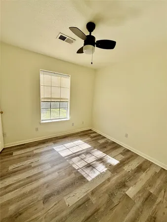 a view of a room with wooden floor and a ceiling fan