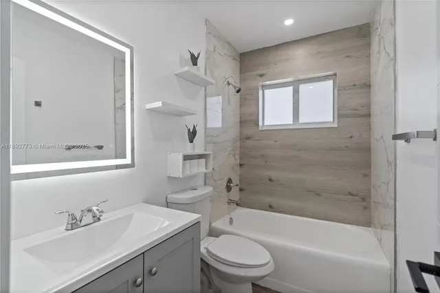 a bathroom with a bathtub shower sink vanity mirror and toilet