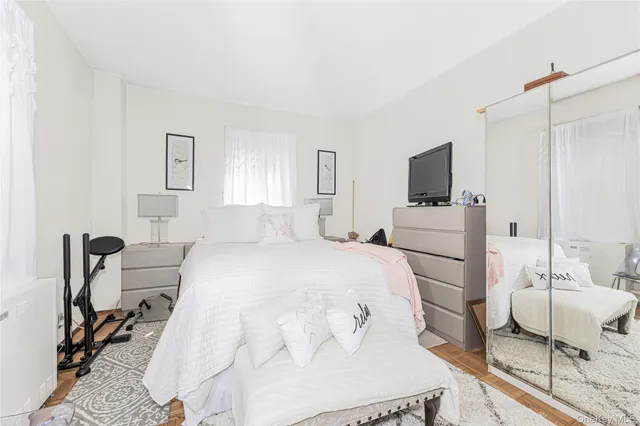 a bedroom with a bed a chair and a flat screen tv