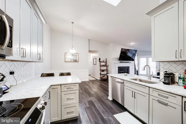 a kitchen with granite countertop white cabinets and stainless steel appliances