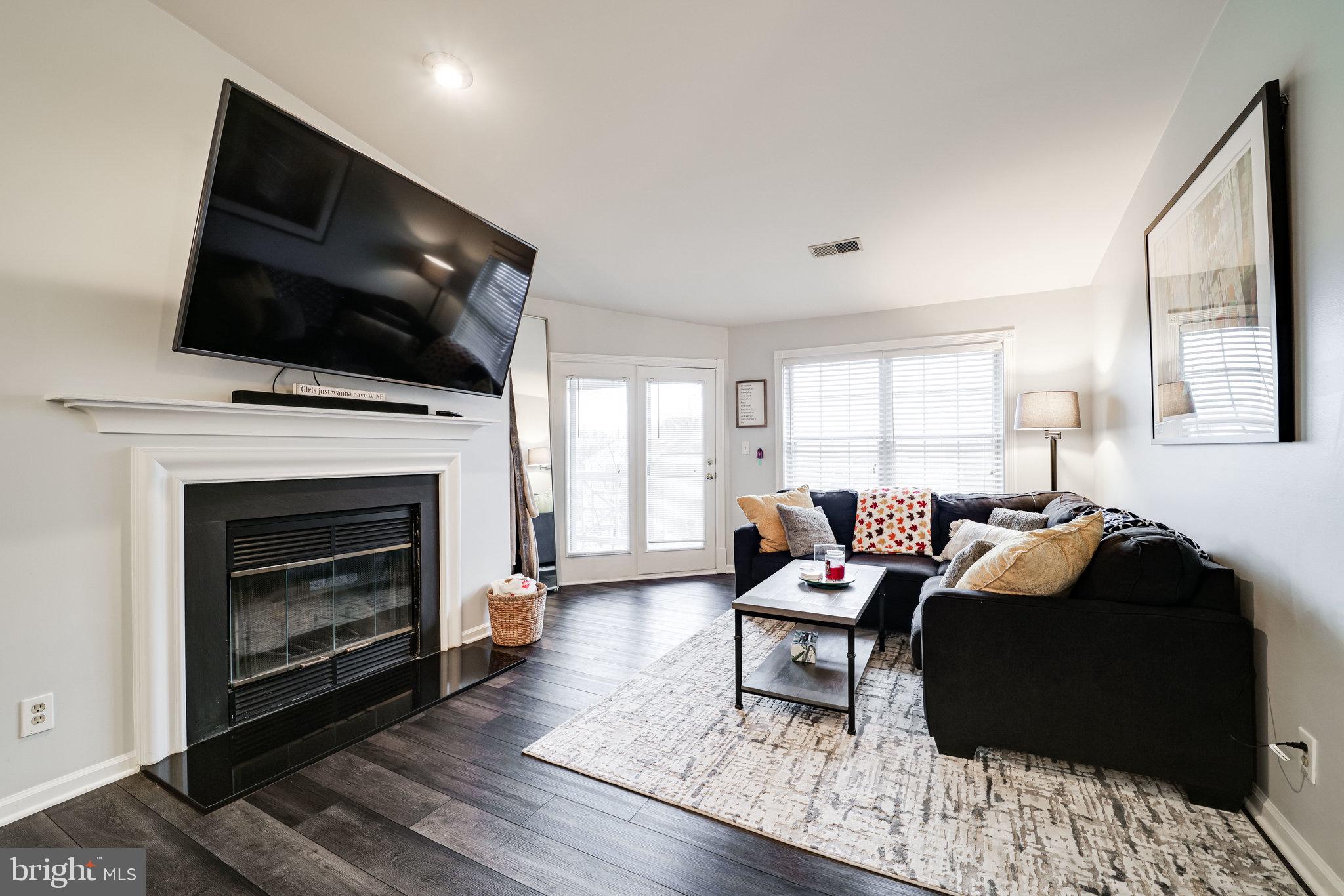 7510 Ashby Lane, Unit J Alexandria, VA 22315 - Photo 3 of 53 a living room with furniture a fireplace and a flat screen tv