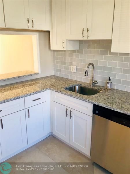 a kitchen with granite countertop white cabinets and a sink