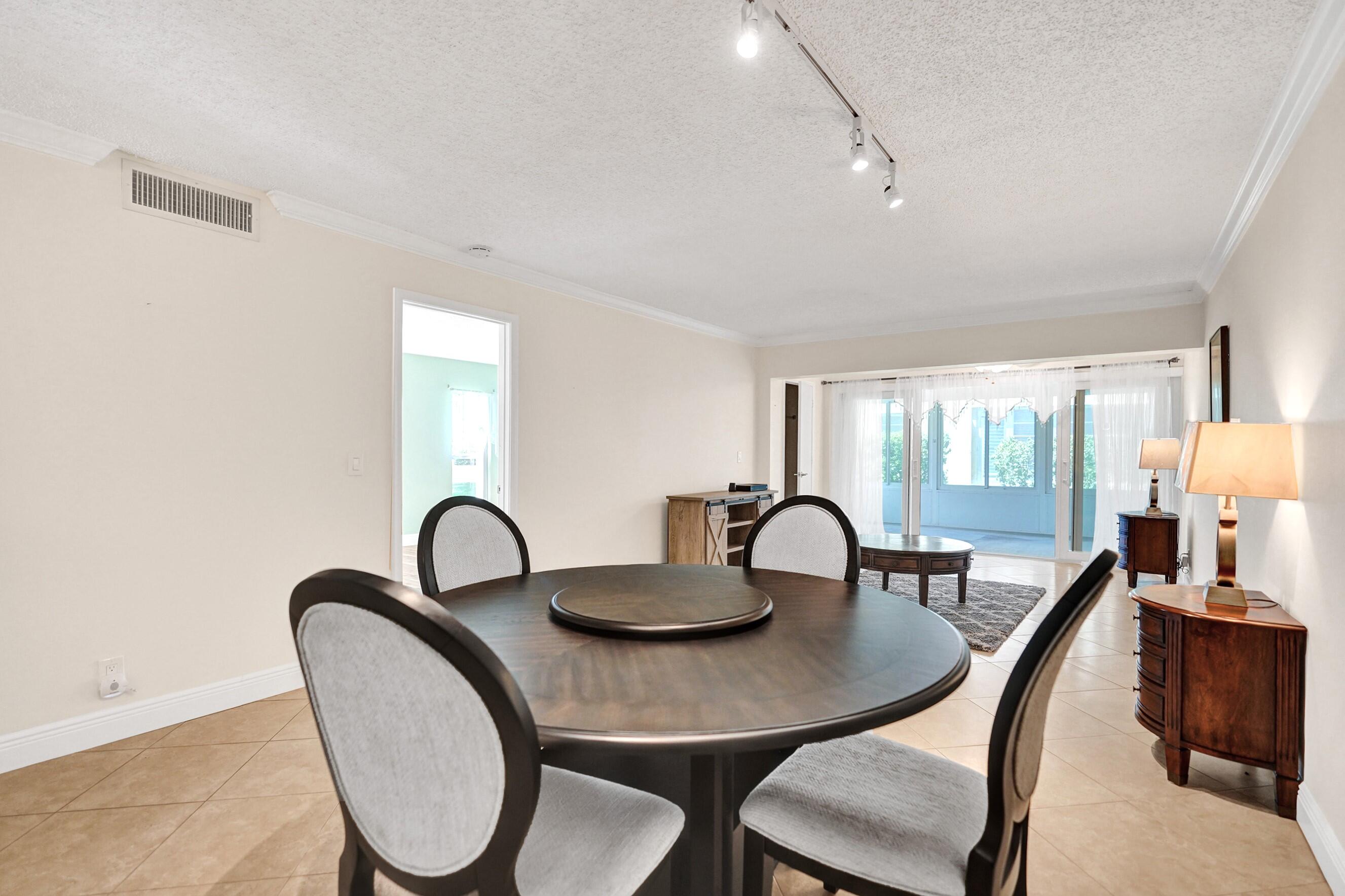 1051 Orange Terrace, Unit 101 Delray Beach, FL 33445 - Photo 29 of 54 a dining room with furniture a window and a kitchen view