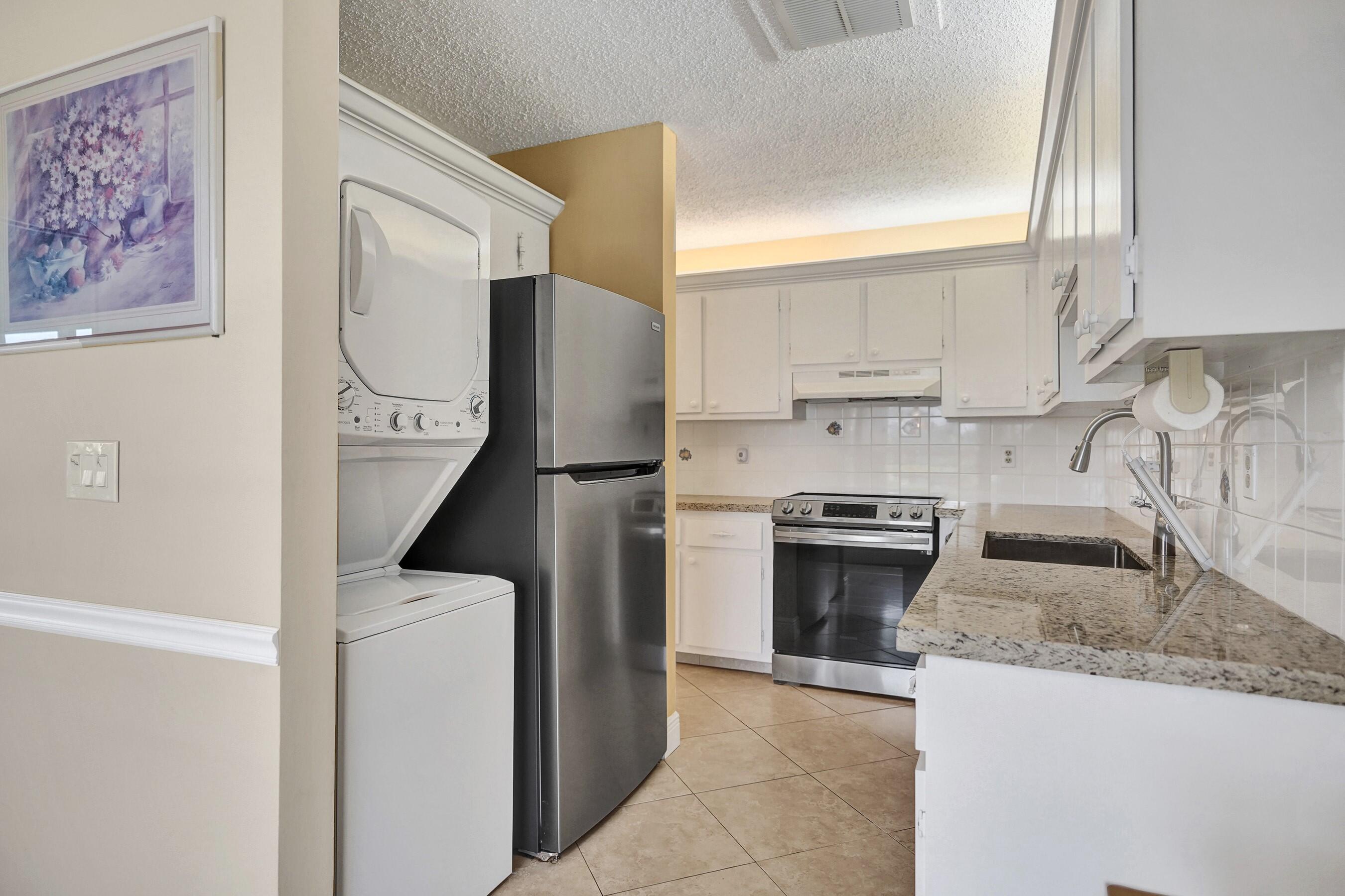 1051 Orange Terrace, Unit 101 Delray Beach, FL 33445 - Photo 31 of 54 a kitchen with stainless steel appliances granite countertop a stove a sink and a refrigerator