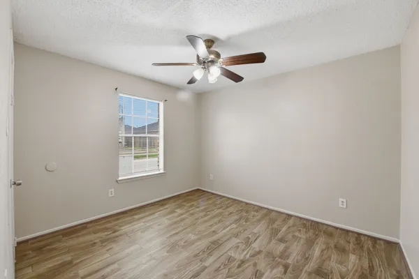 an empty room with a window and ceiling fan
