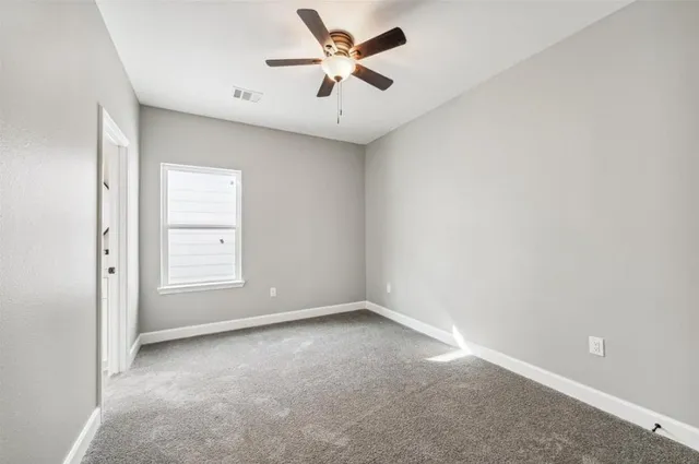 an empty room with a window and a ceiling fan