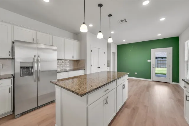 a kitchen with kitchen island a refrigerator a sink and a stove