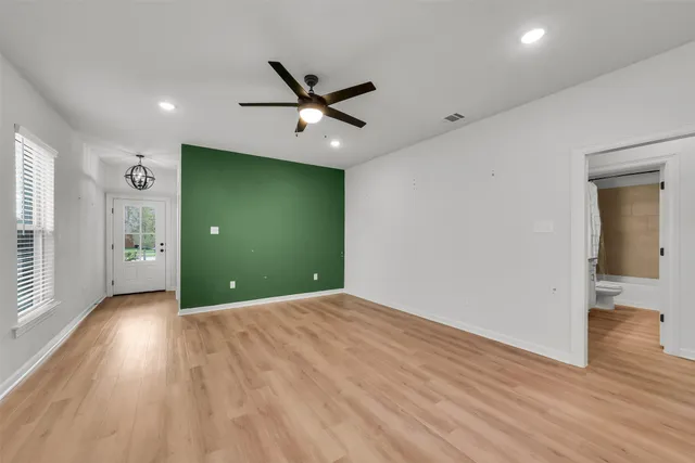 a view of empty room with wooden floor and fan