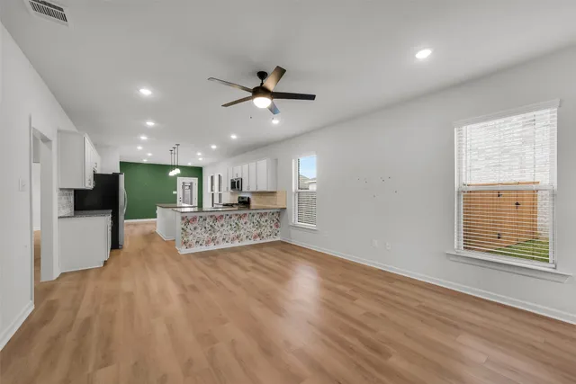 a view of an empty room with kitchen and kitchen view