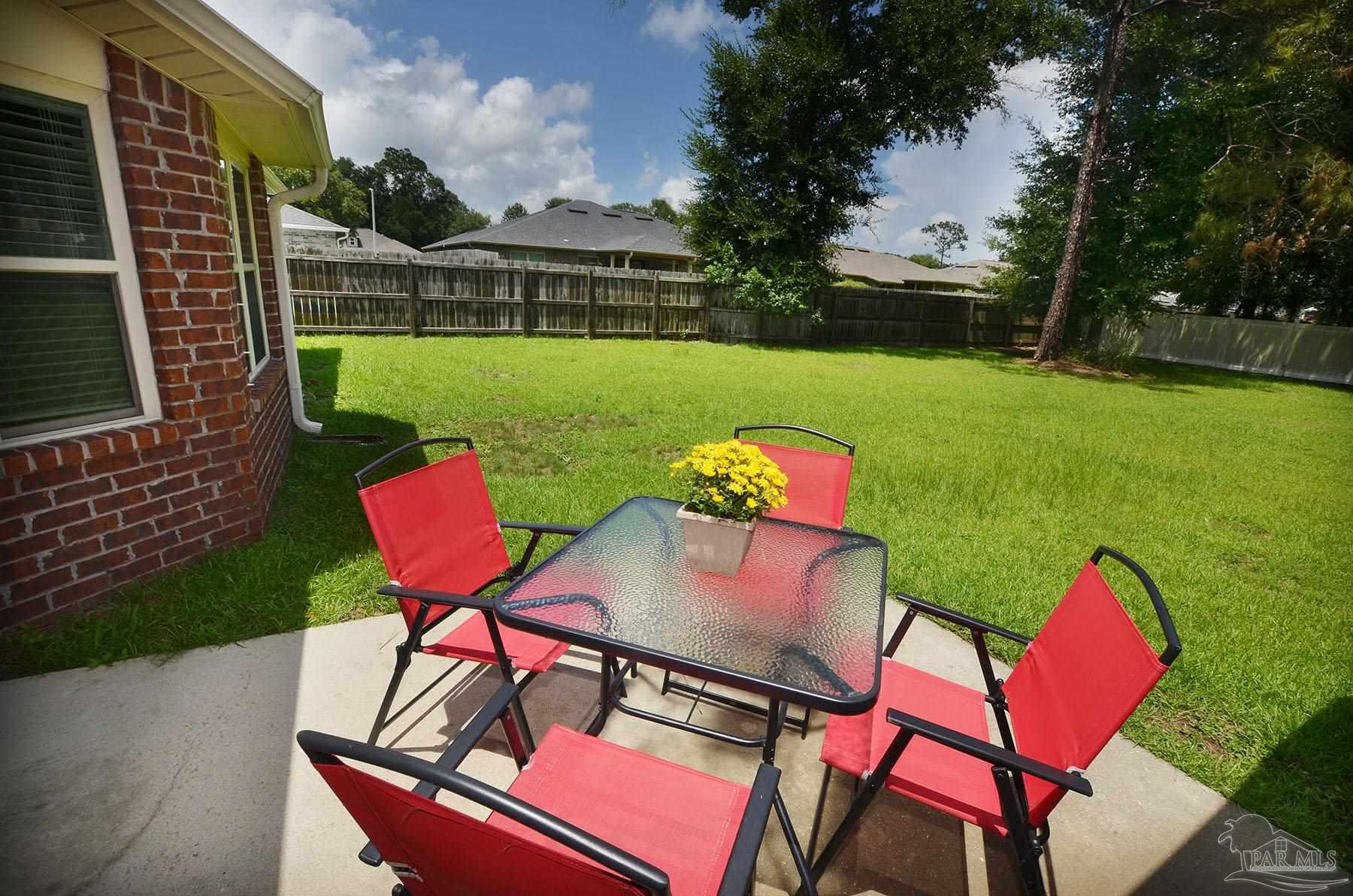 5709 Mill Stream Way Pace, FL 32571 - Photo 46 of 48 a view of a chairs and table in patio with a yard