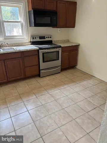 a kitchen with granite countertop a stove a sink and a microwave