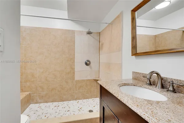 a bathroom with a granite countertop sink a mirror and shower