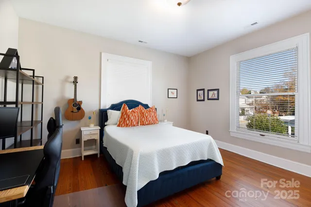 a bedroom with a bed a window and wooden floor