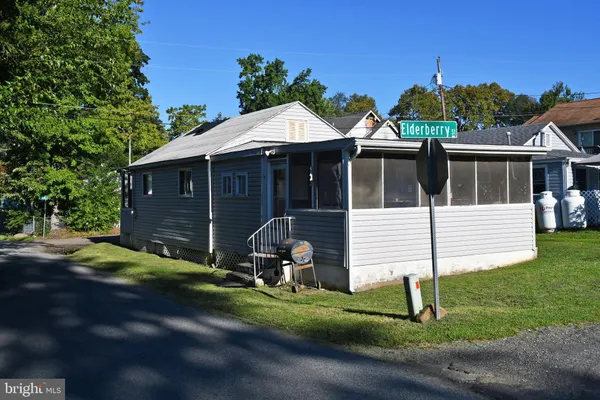 a view of a white house with a small yard and large trees