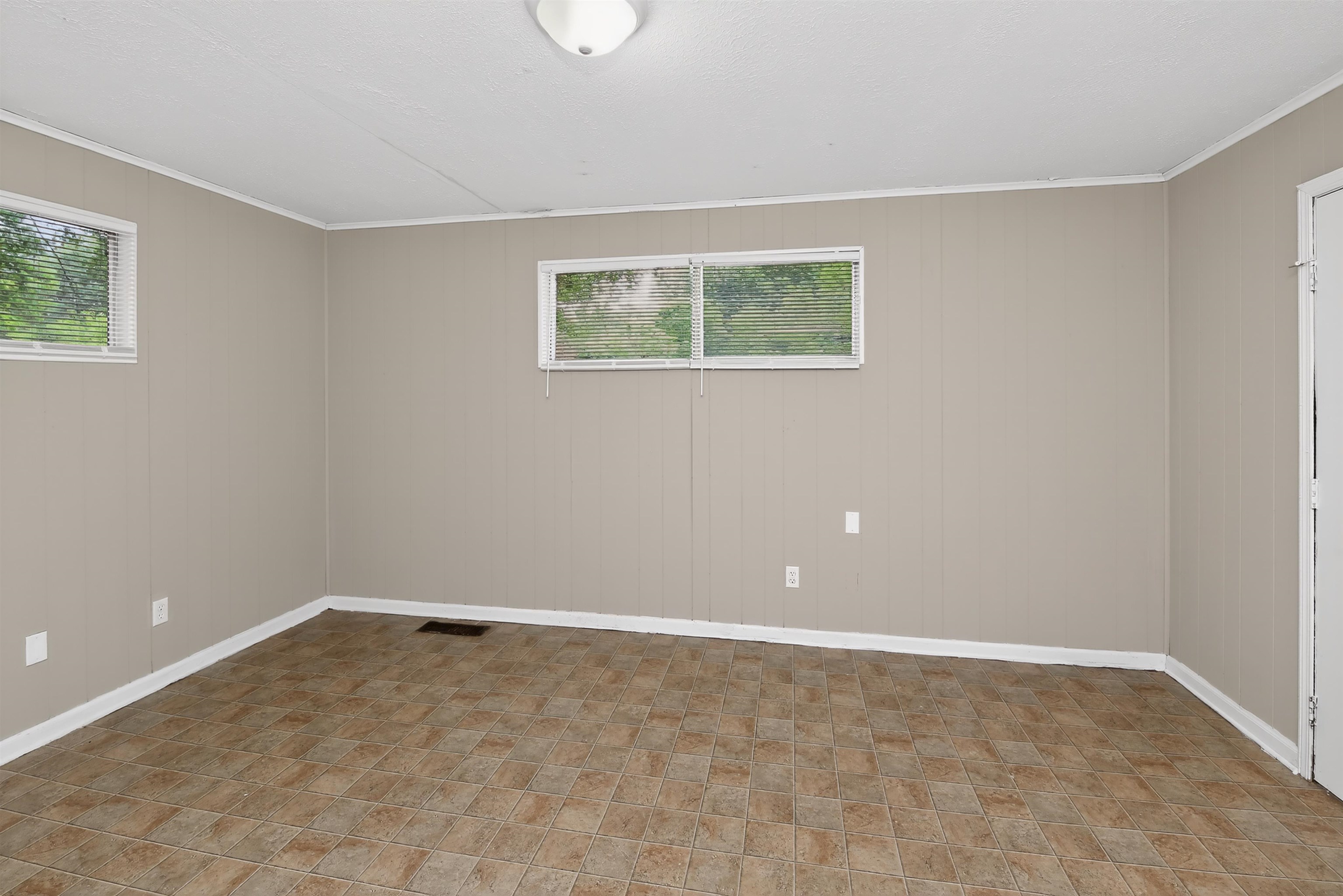 2840 Allen Road Memphis, TN 38128 - Photo 19 of 31 Neutral-toned room featuring a panel accent wall, multiple windows, and patterned floor tiling