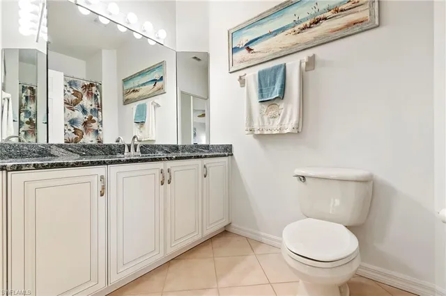 a bathroom with a granite countertop toilet sink and mirror