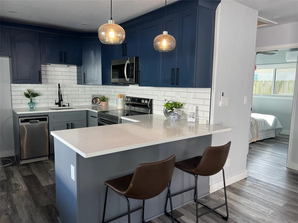 13246 4th Street East Madeira Beach, FL 33708 - Photo 12 of 23 a kitchen with a dining table chairs cabinets and stainless steel appliances