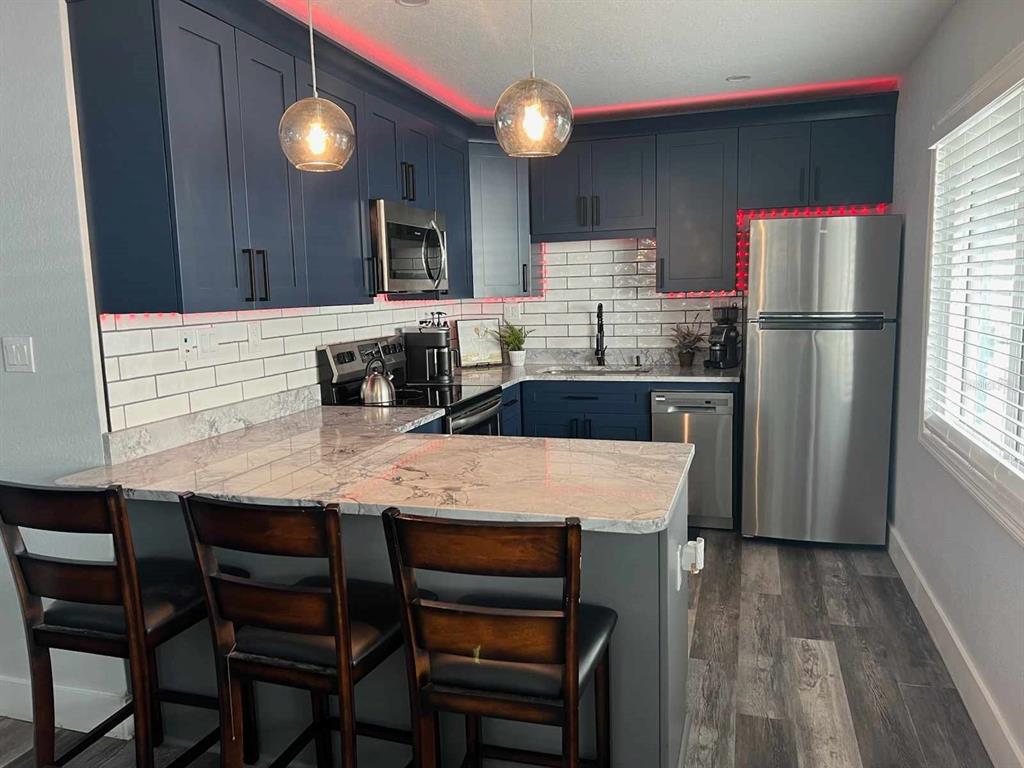 13246 4th Street East Madeira Beach, FL 33708 - Photo 19 of 23 a kitchen with stainless steel appliances granite countertop a table chairs refrigerator and sink