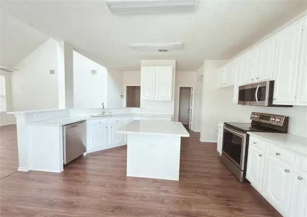 a large kitchen with a stove top oven and white cabinets