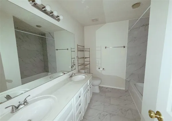 a bathroom with a granite countertop sink a toilet and shower