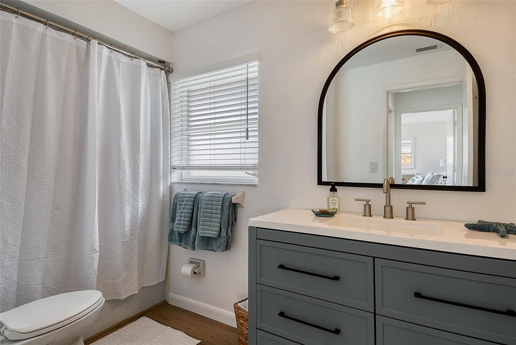 6722 Roxbury Drive Sarasota, FL 34231 - Photo 42 of 87 a bathroom with a toilet a sink a mirror a shower and a window
