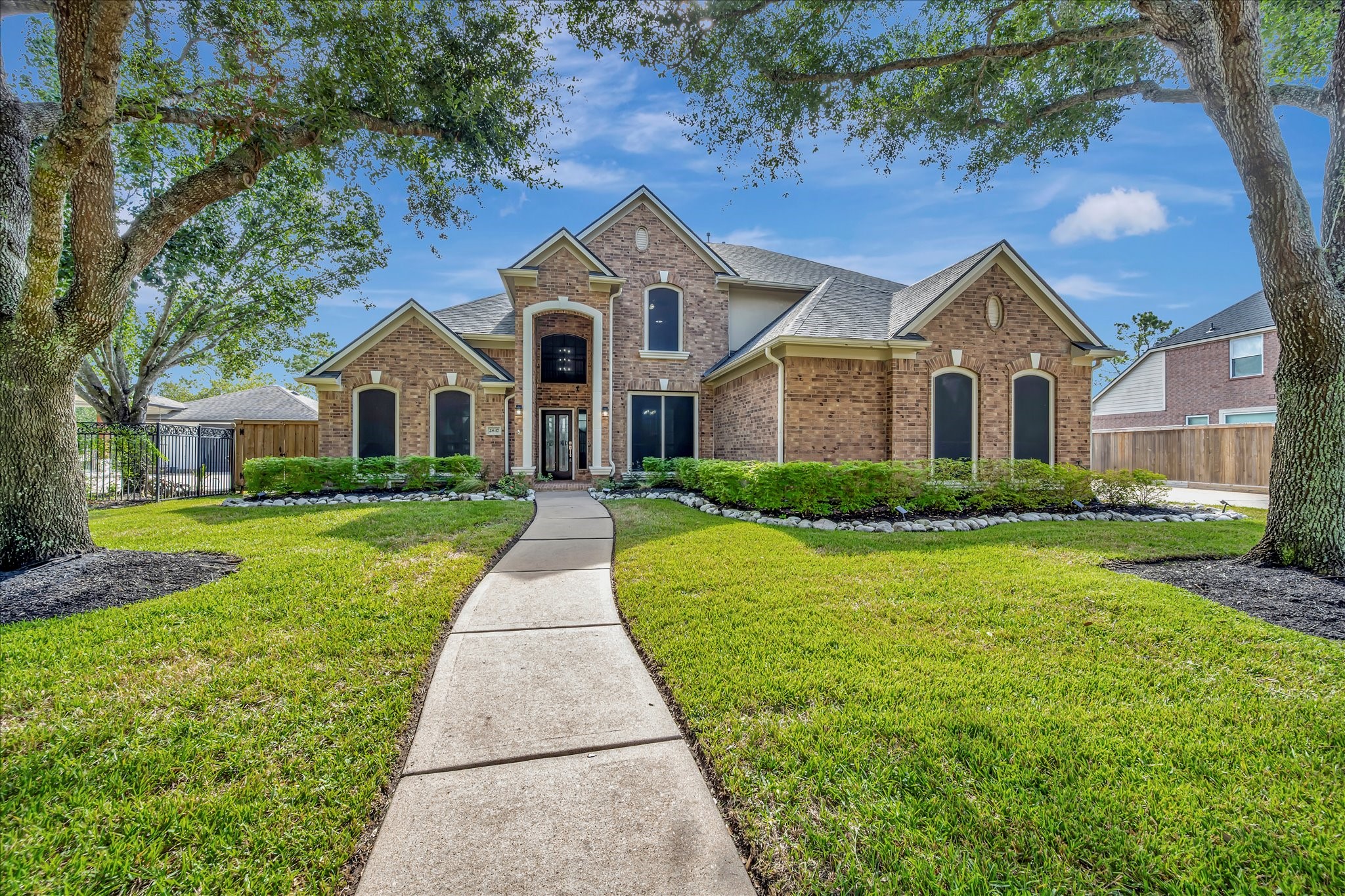 Stunning brick home with elegant architecture, lush landscaping, and a welcoming pathway, perfect for your next chapter.