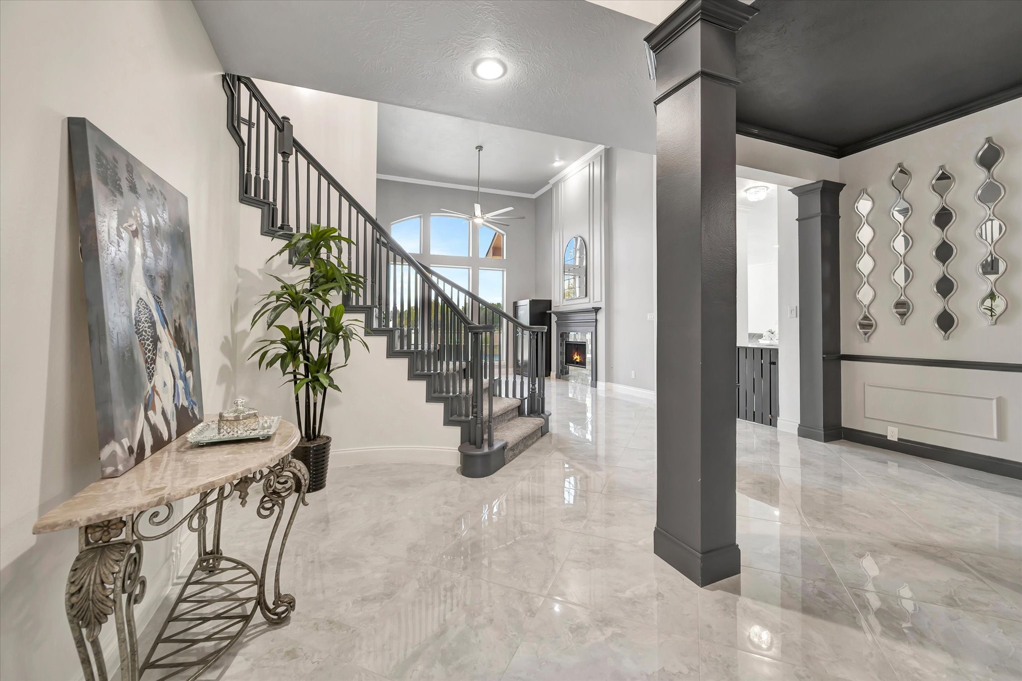 2847 Everett Drive Friendswood, TX 77546 - Photo 12 of 50 This photo showcases a spacious and elegant entryway and a chic black staircase. The open design leads into a bright formal living area with large windows and a fireplace, creating an inviting atmosphere.