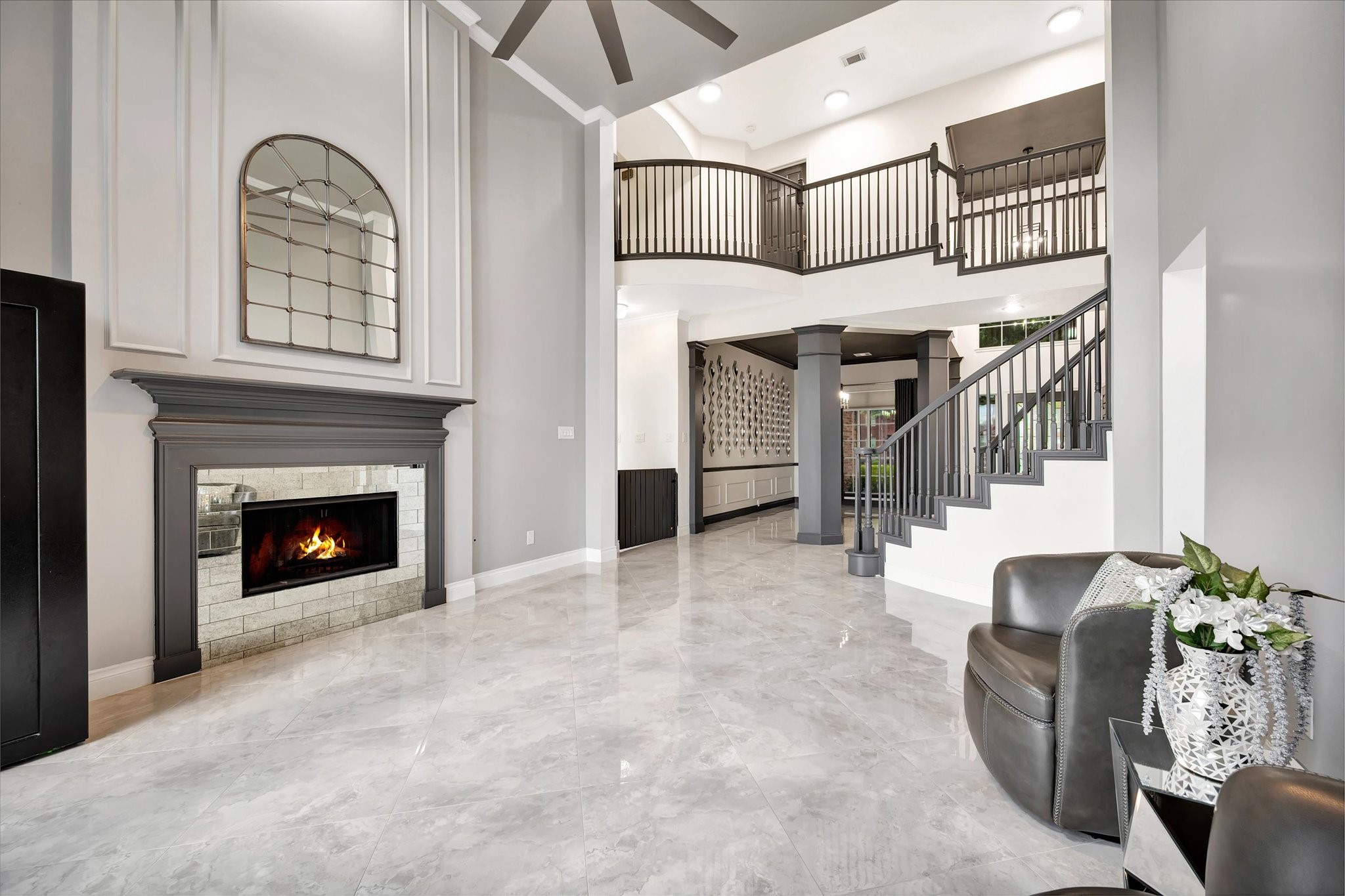 2847 Everett Drive Friendswood, TX 77546 - Photo 15 of 50 This elegant living space features a high ceiling, a modern fireplace, and a striking staircase with sleek railings. The open layout and large windows provide ample natural light, complemented by polished floors. Perfect for stylish and comfortable living.