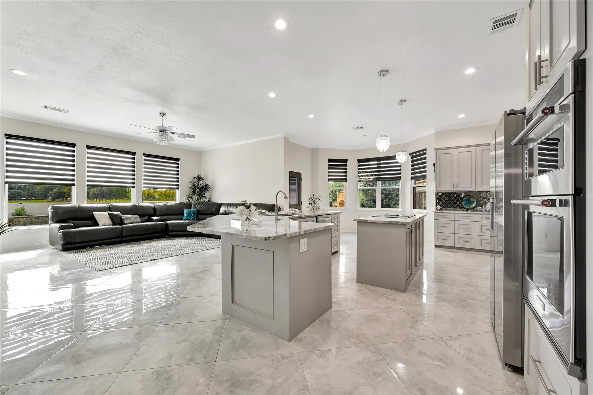 2847 Everett Drive Friendswood, TX 77546 - Photo 18 of 50 Experience modern elegance in this open-concept space, featuring a sleek kitchen with dual islands, one with a Tesla Induction cook-top, Stainless steel appliances, and ample cabinetry. Enjoy abundant natural light through expansive windows with stylish blinds. Polished tile flooring and a neutral palette add a touch of sophistication.