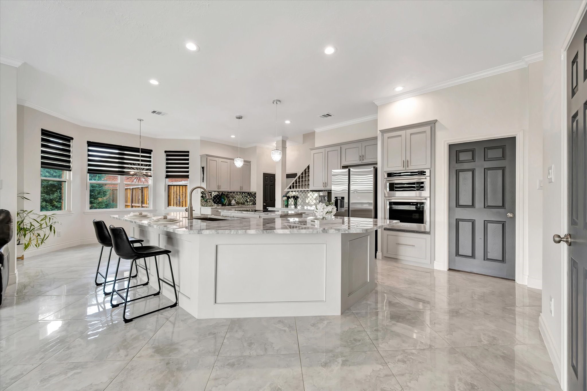2847 Everett Drive Friendswood, TX 77546 - Photo 20 of 50 This modern kitchen features sleek grey cabinetry, stainless steel appliances, and a spacious center island with seating. The tile flooring and large windows provide a bright, open feel, complemented by chic pendant lighting.
