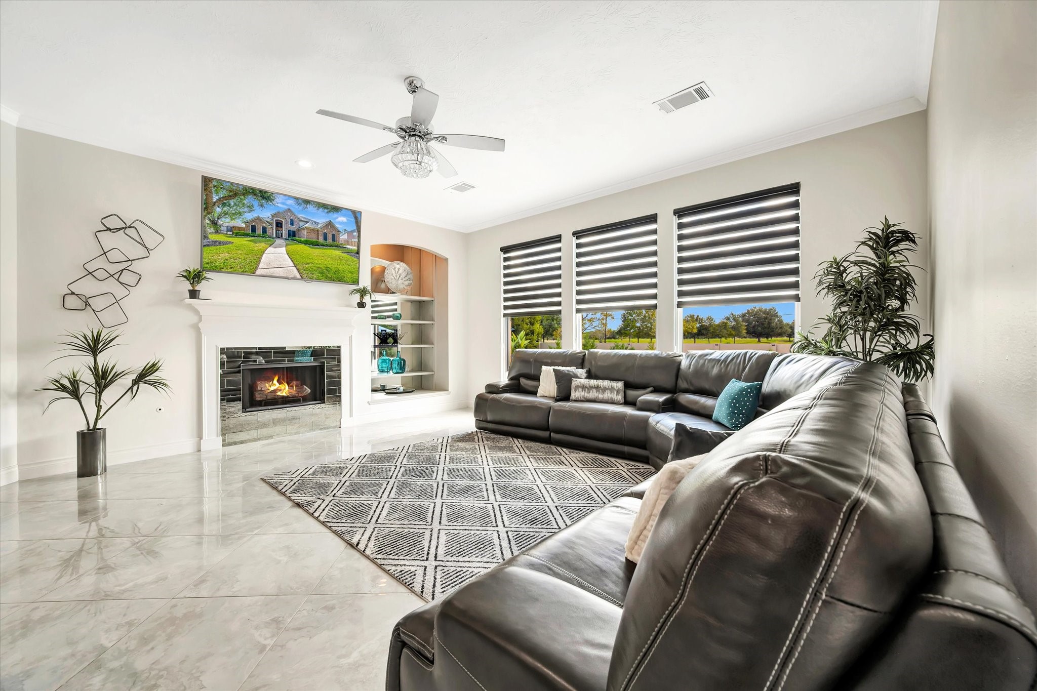 2847 Everett Drive Friendswood, TX 77546 - Photo 27 of 50 This living room features a spacious, modern design with a cozy fireplace. Natural light streams through wide windows with stylish blinds, and the room is accented by a sleek ceiling fan. Perfect for relaxed living and entertaining.