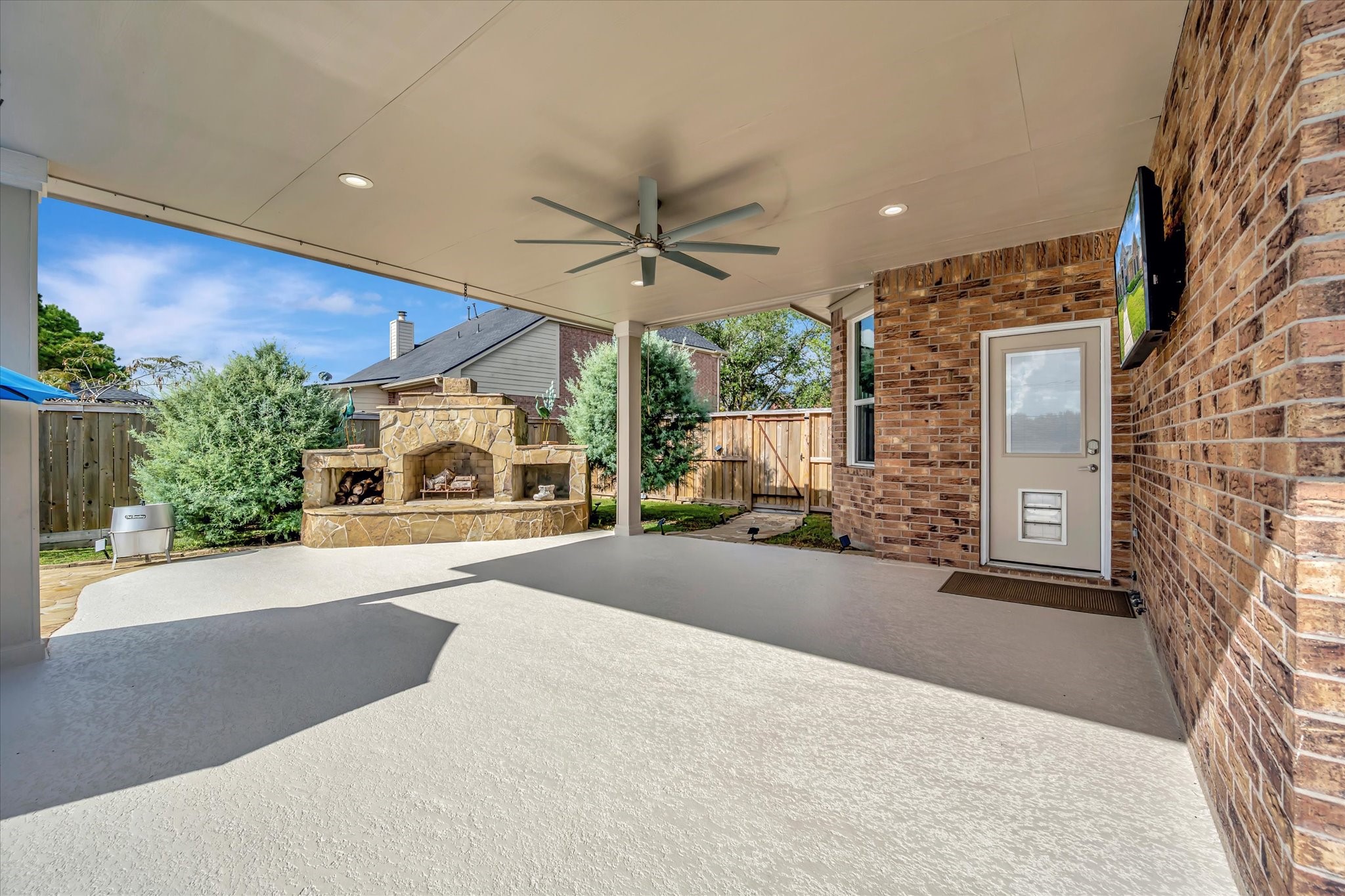 2847 Everett Drive Friendswood, TX 77546 - Photo 3 of 50 Spacious covered patio with a stunning stone fireplace, perfect for outdoor entertaining and relaxation.
