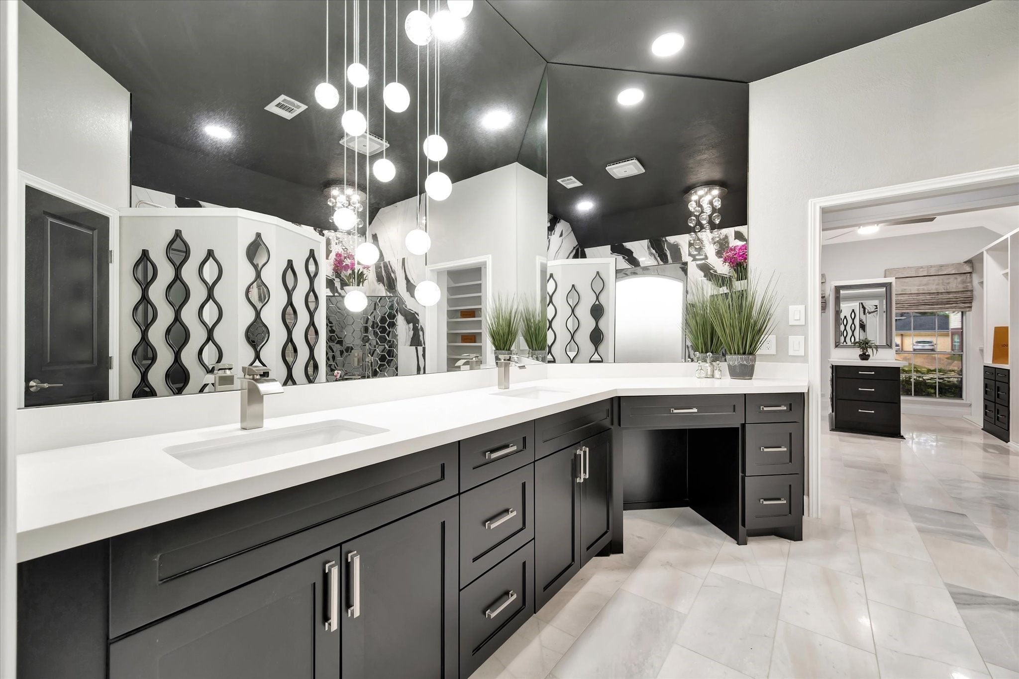 2847 Everett Drive Friendswood, TX 77546 - Photo 35 of 50 This modern bathroom features a sleek black and white design with ample counter space and cabinetry. The room boasts stylish lighting fixtures, marble floors, a large mirror, and decorative elements, creating a luxurious and contemporary feel.
