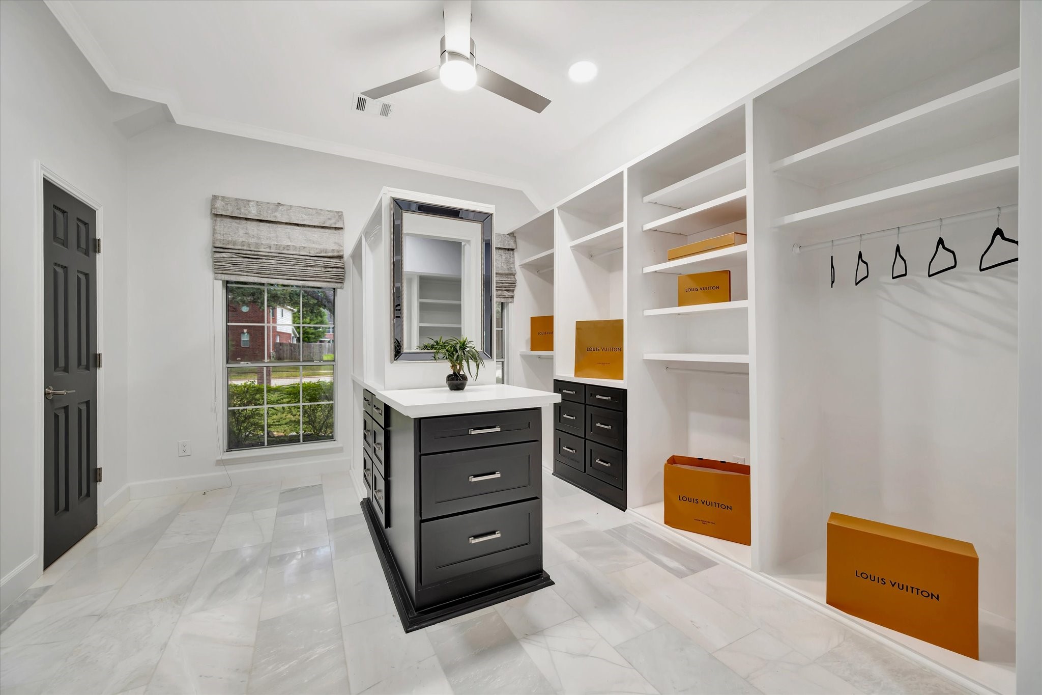 2847 Everett Drive Friendswood, TX 77546 - Photo 38 of 50 This spacious, well-lit walk-in closet features white shelving, a central island with drawers, and large windows for natural light. It's a stylish and functional space for organization and storage.