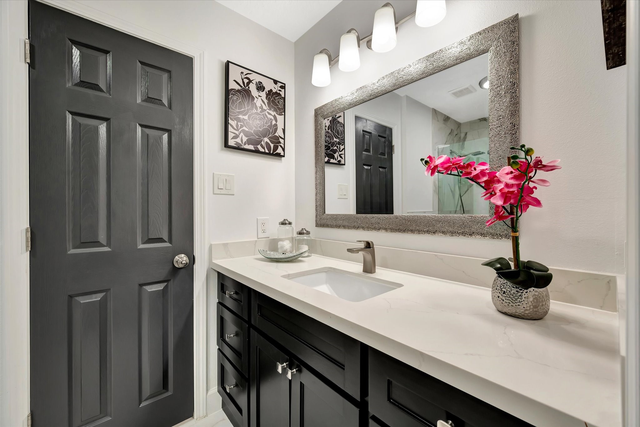 2847 Everett Drive Friendswood, TX 77546 - Photo 42 of 50 This bathroom features a modern design with a sleek, black vanity and white countertop. It includes a large framed mirror and stylish lighting