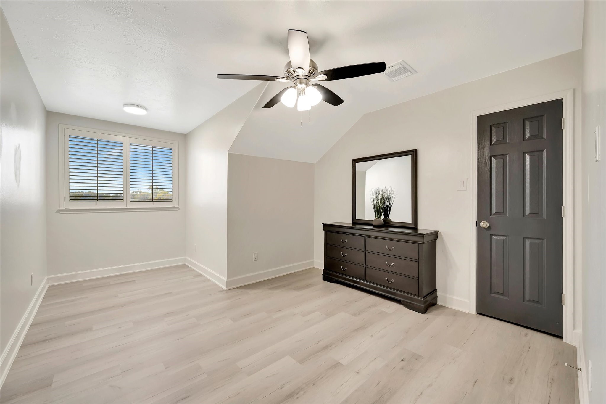 2847 Everett Drive Friendswood, TX 77546 - Photo 46 of 50 This bright, spacious bedroom features light wood flooring, a ceiling fan, and a large window with blinds while the room's neutral walls and trim offer a modern feel.