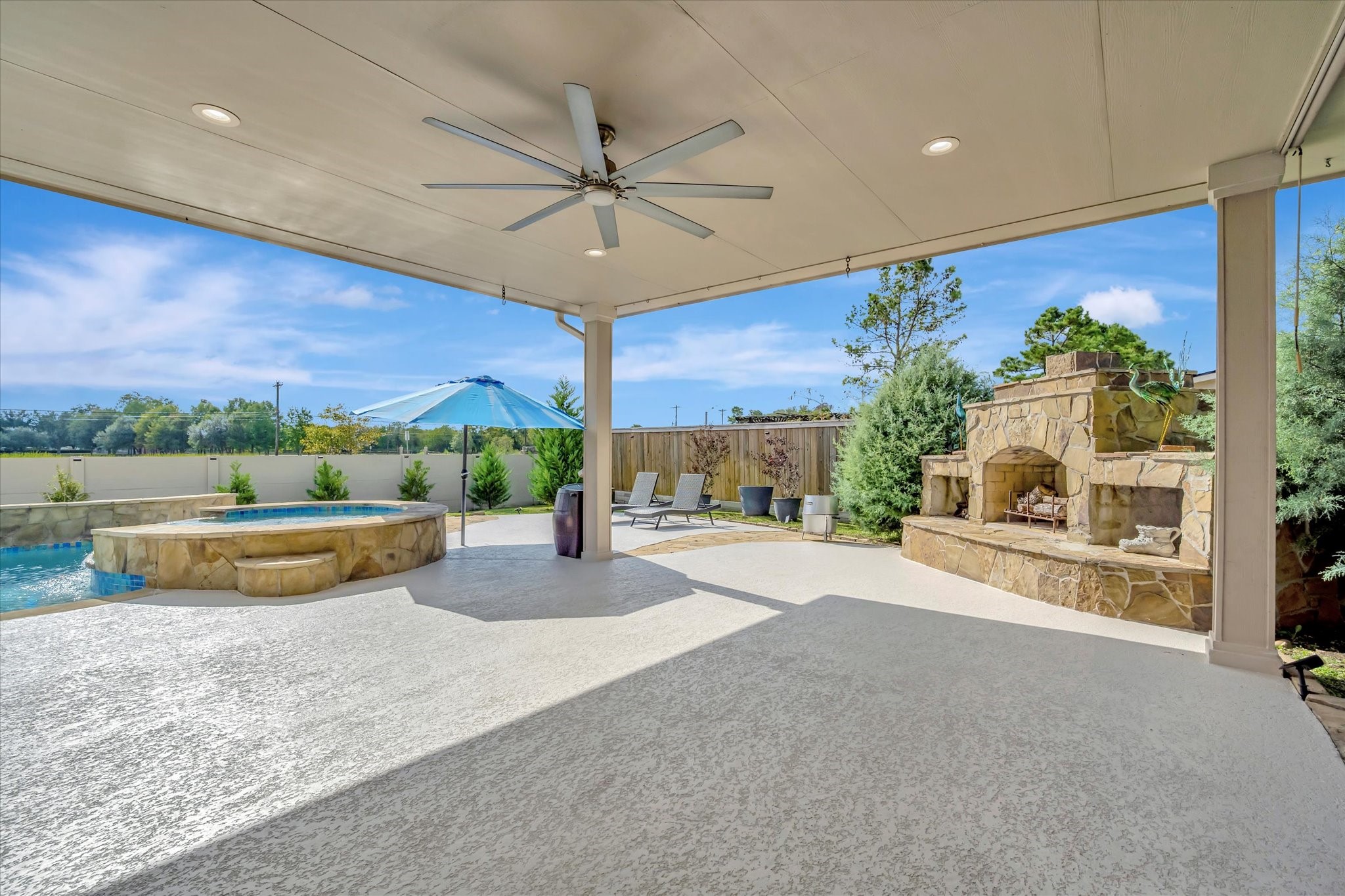 2847 Everett Drive Friendswood, TX 77546 - Photo 5 of 50 This backyard features a spacious covered patio with a ceiling fan, an inviting stone fireplace, and a luxurious pool with hot tub. Perfect for outdoor relaxation and entertaining
