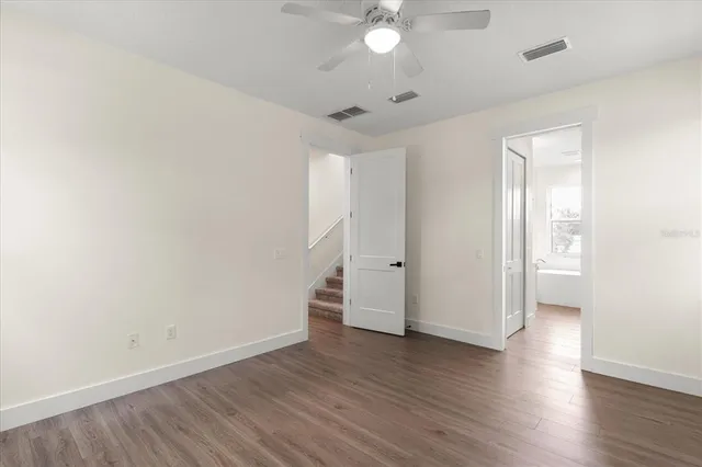 an empty room with wooden floor and a ceiling fan