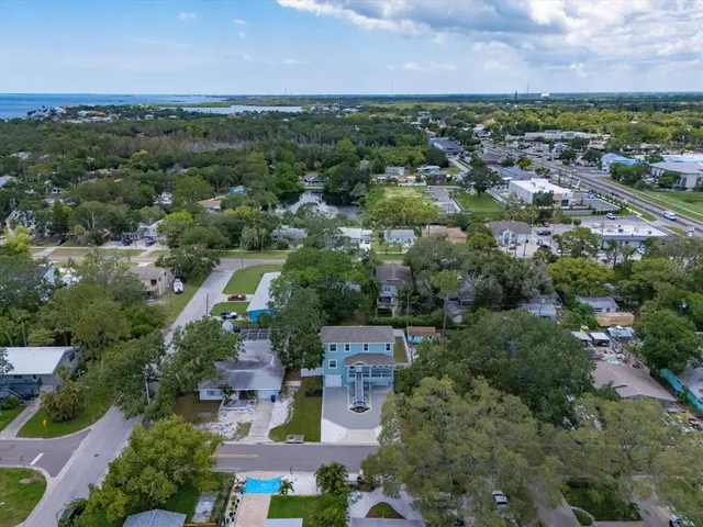 an aerial view of a city with lots of residential buildings green landscape and ocean view