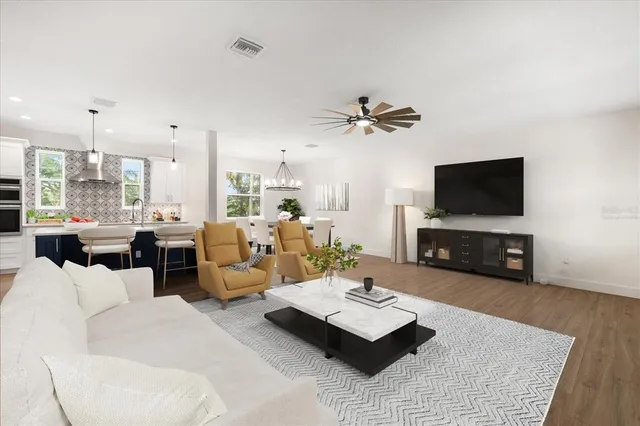 a living room with furniture a flat screen tv and kitchen view