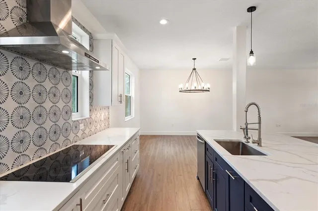 a kitchen with stainless steel appliances granite countertop a sink a stove and a wooden floors