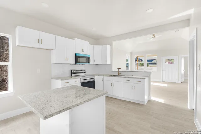 a kitchen with granite countertop white cabinets and stainless steel appliances