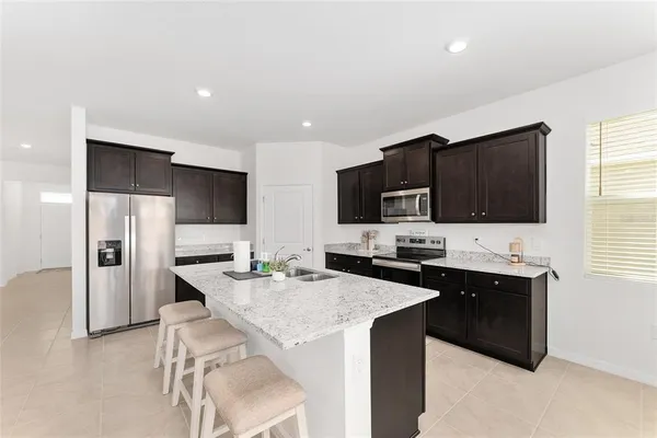 a kitchen with granite countertop kitchen island a sink stainless steel appliances and cabinets