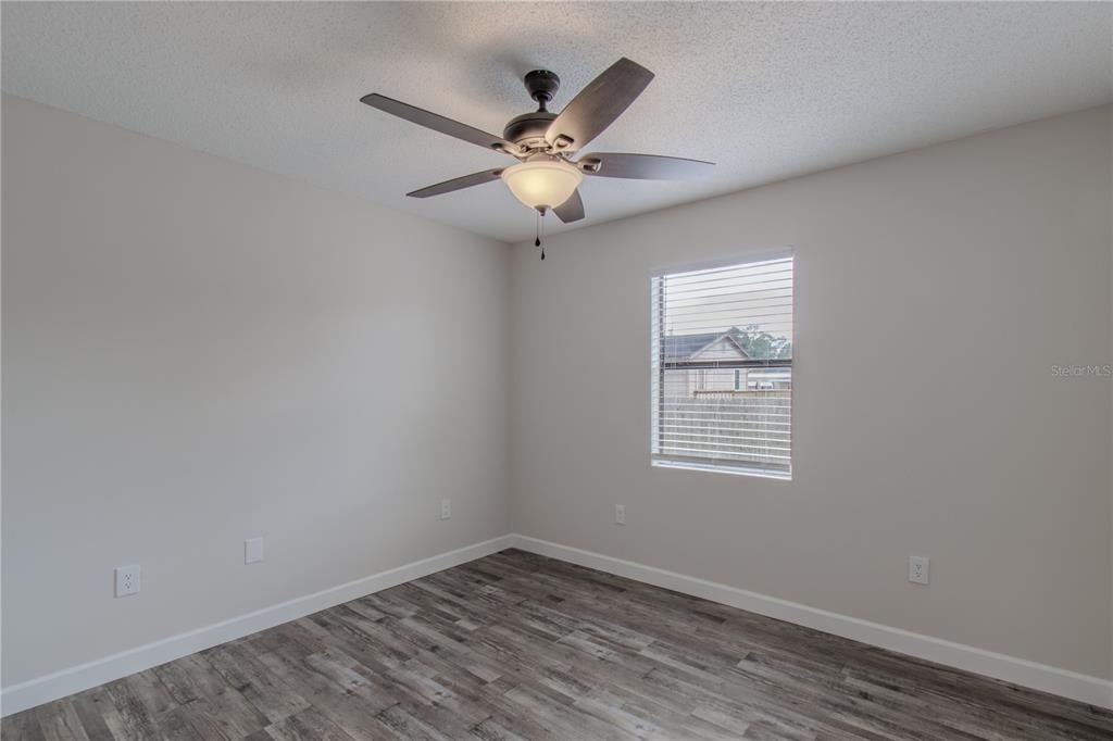 24024 Deer Road Astor, FL 32102 - Photo 14 of 22 an empty room with wooden floor fan and windows