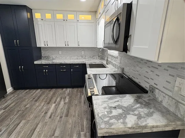 a kitchen with stainless steel appliances granite countertop a sink a stove a microwave a sink and a refrigerator