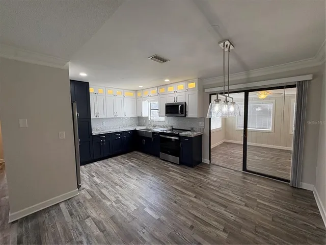 a kitchen with stainless steel appliances kitchen island granite countertop a refrigerator a sink and wooden floor