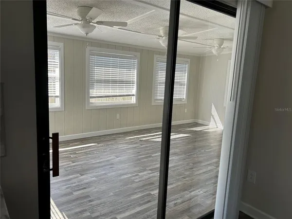 a view of empty room with wooden floor and fan